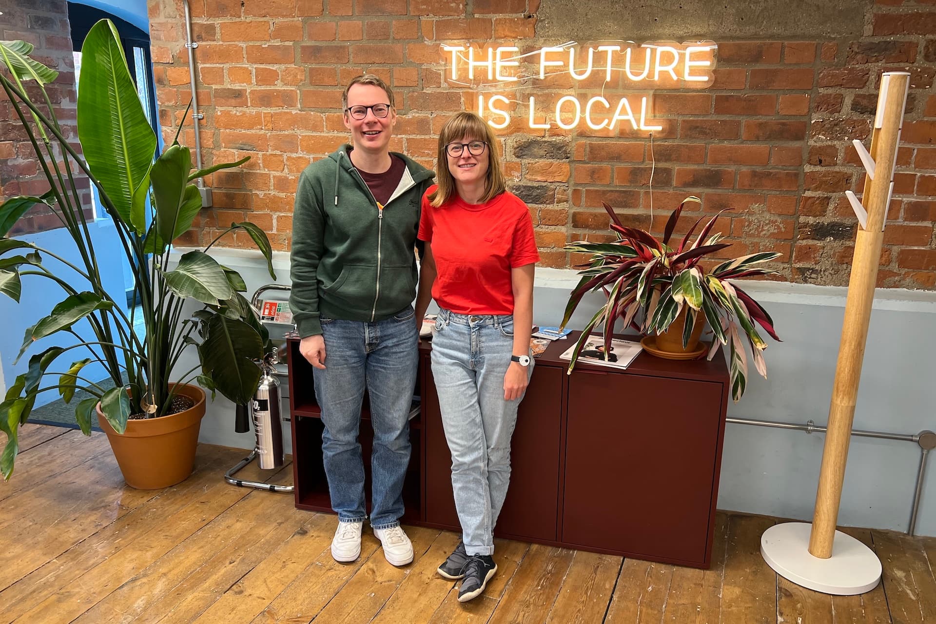 The DanceCloud team beneath a neon sign reading "The future is local"